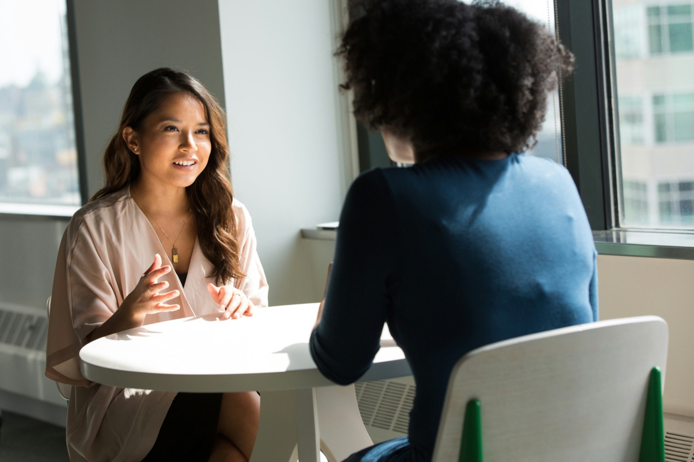 Two people talking a project through at a table by the window
